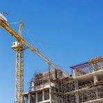 Hospital building under construction with cranes against a blue sky.